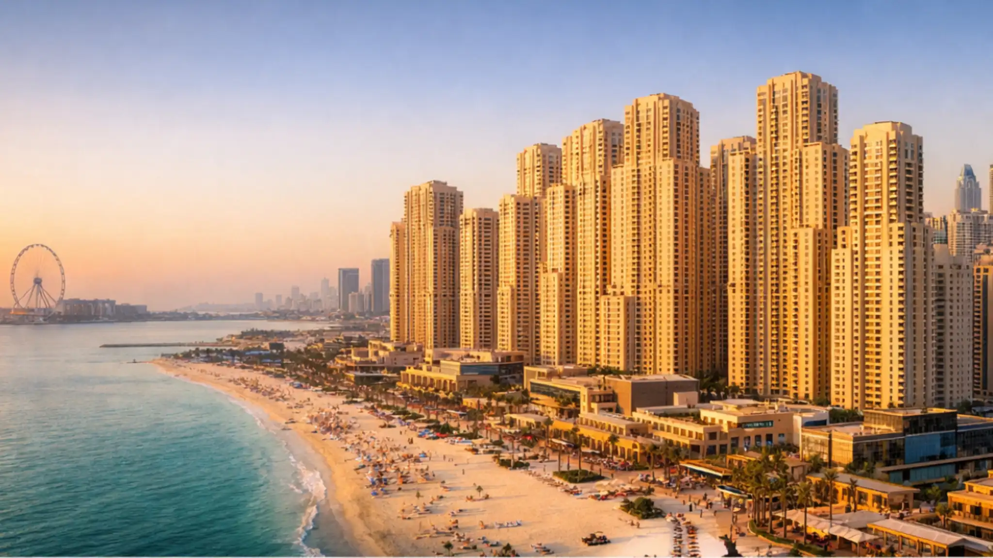 Golden-hour aerial view of Jumeirah Beach Residence beachfront towers in Dubai, showing luxury high-rise apartments, sandy beach, Arabian Gulf coastline, and vibrant promenade lifestyle.